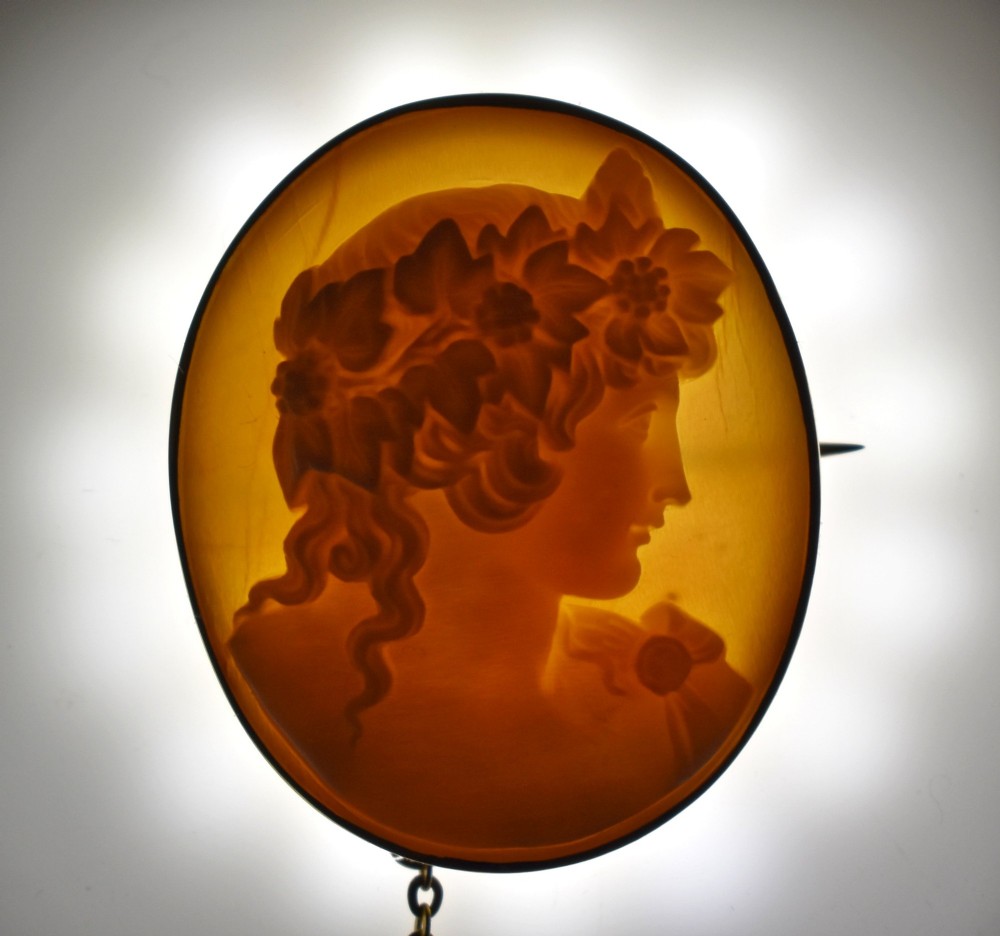 An oval Victorian shell cameo brooch depicting a relief profile carving of Antinous adorned with a floral wreath, set in a gold frame. View II