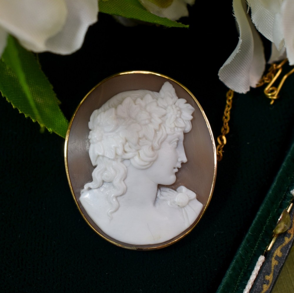 An oval Victorian shell cameo brooch depicting a relief profile carving of Antinous adorned with a floral wreath, set in a gold frame. View III