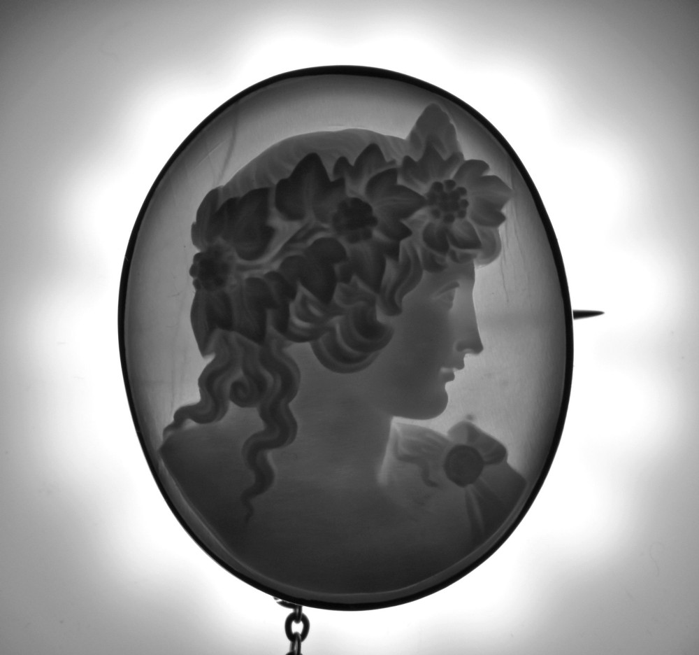 An oval Victorian shell cameo brooch depicting a relief profile carving of Antinous adorned with a floral wreath, set in a gold frame. View IX