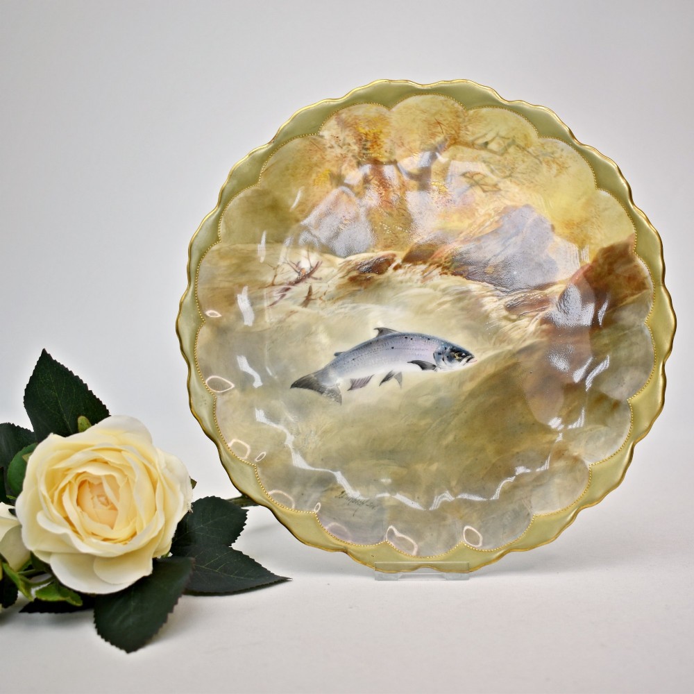 A set of four circular porcelain cabinet plates with scalloped gold rims, each featuring a central hand-painted scene of fish swimming in natural river settings. View II