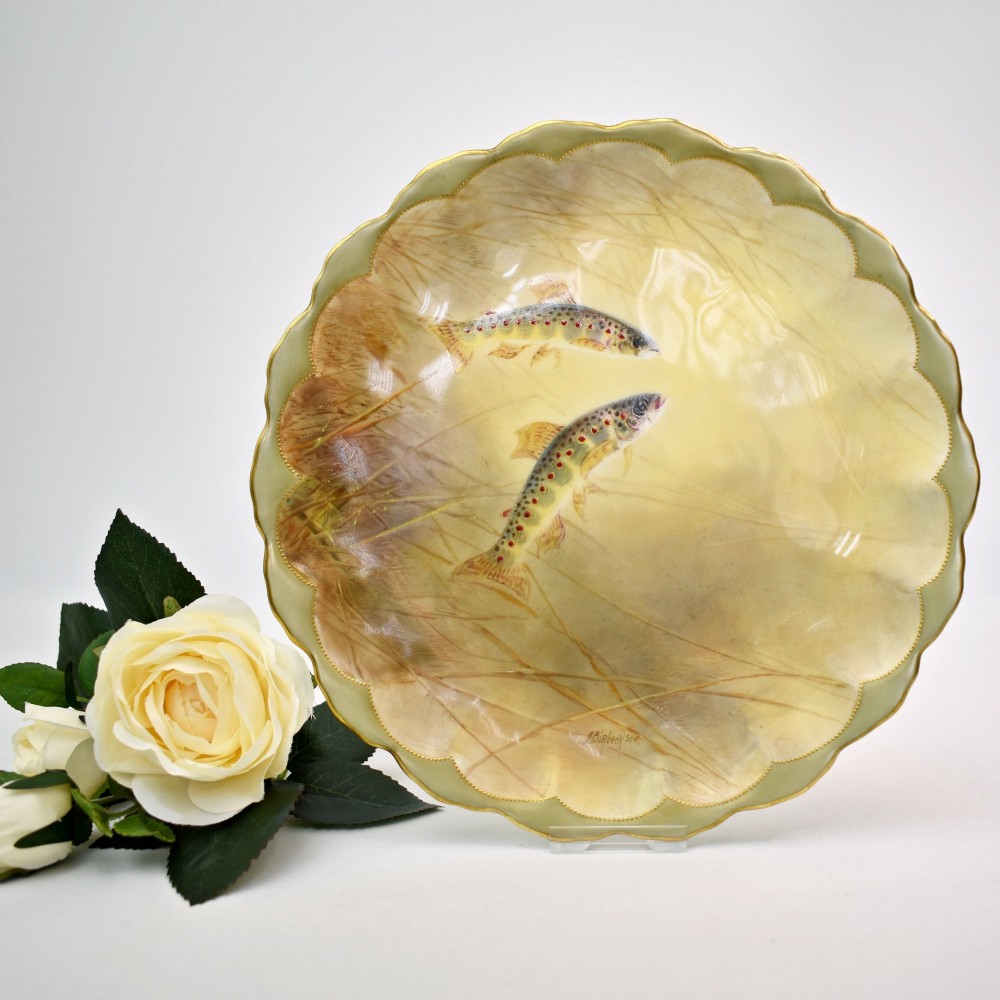 A set of four circular porcelain cabinet plates with scalloped gold rims, each featuring a central hand-painted scene of fish swimming in natural river settings. View IV