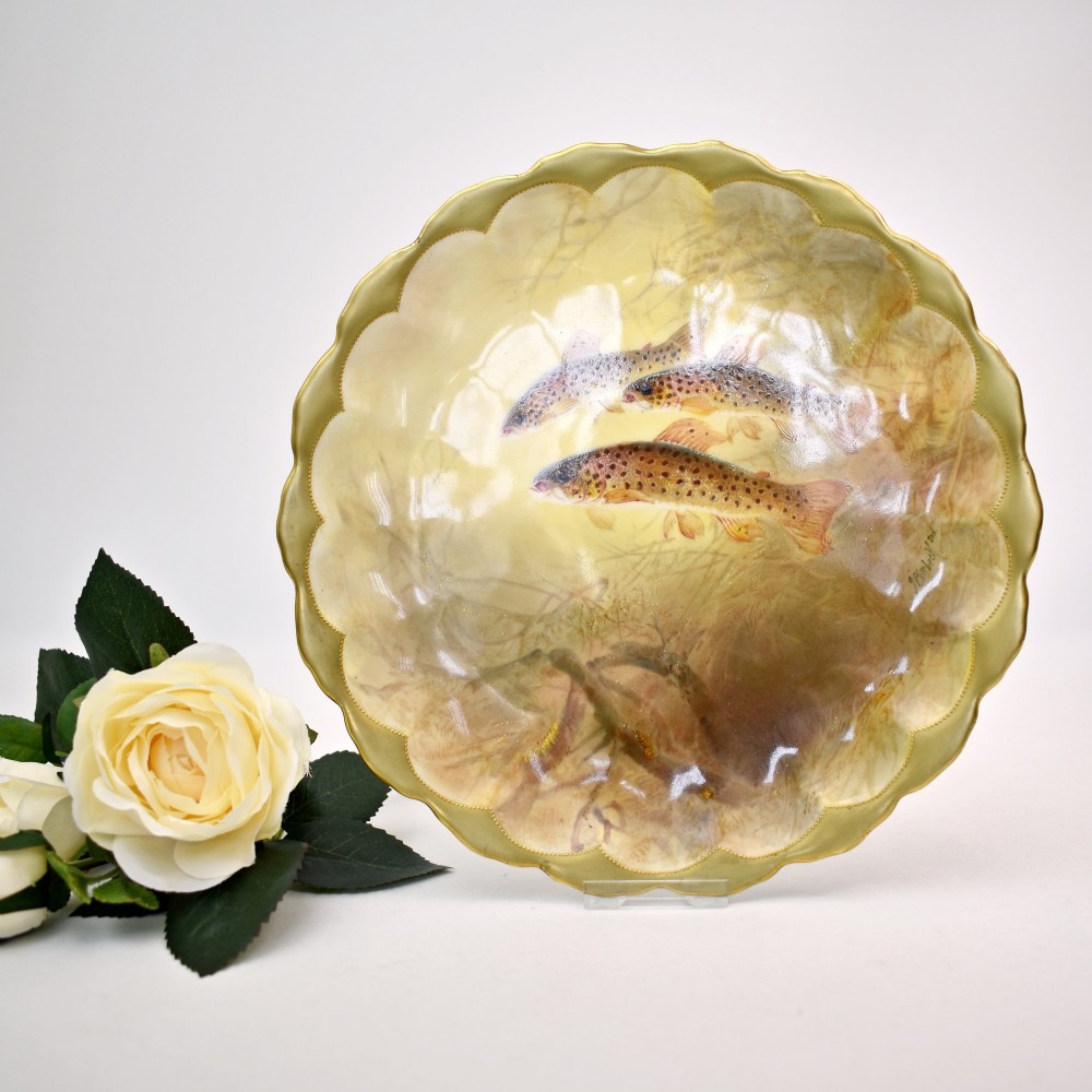 A set of four circular porcelain cabinet plates with scalloped gold rims, each featuring a central hand-painted scene of fish swimming in natural river settings. View V