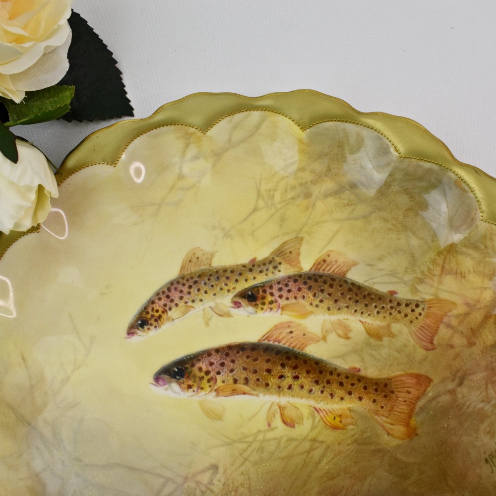 A set of four circular porcelain cabinet plates with scalloped gold rims, each featuring a central hand-painted scene of fish swimming in natural river settings. View VIII