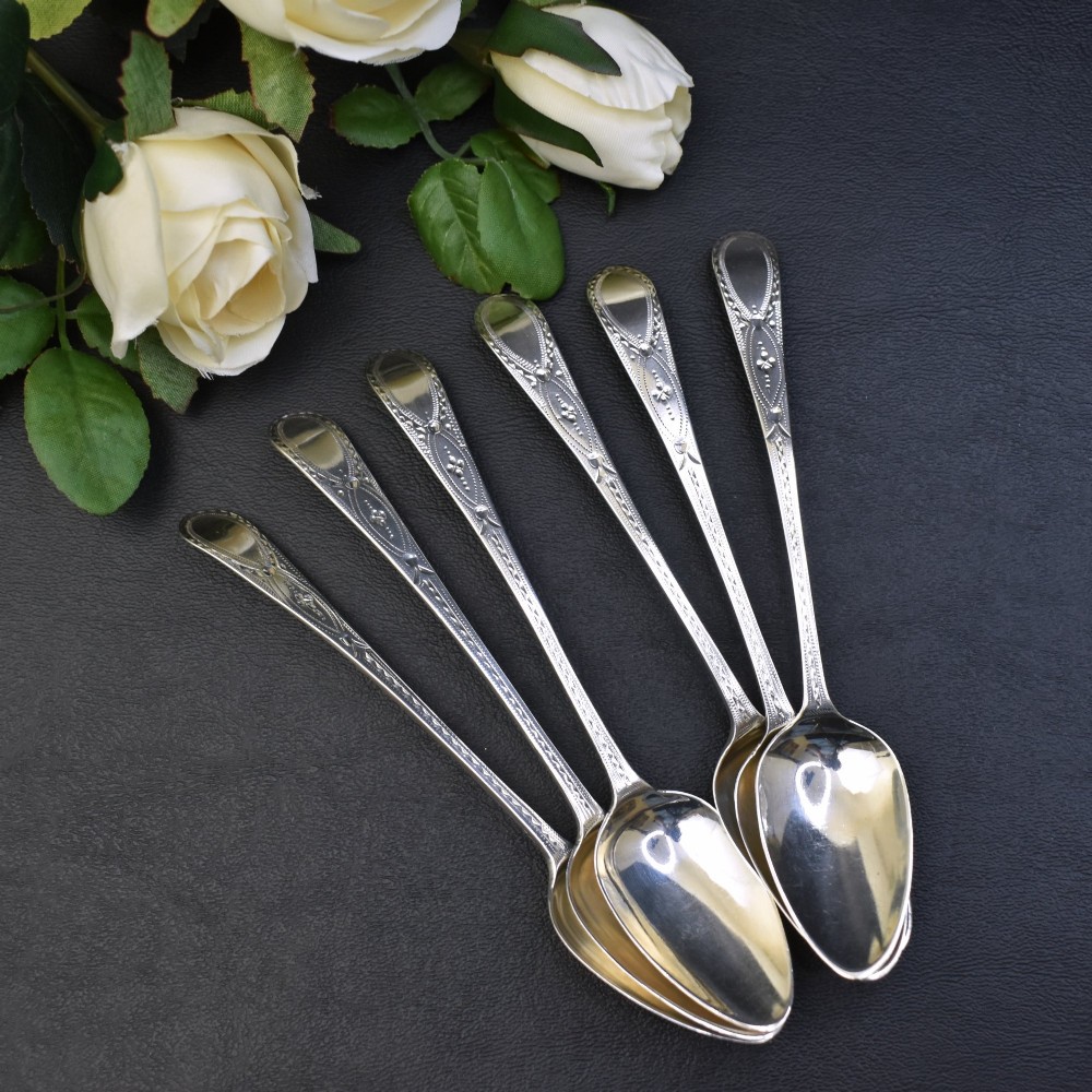 A set of six George III sterling silver teaspoons featuring bright-cut engraved stems and smooth oval bowls. View II