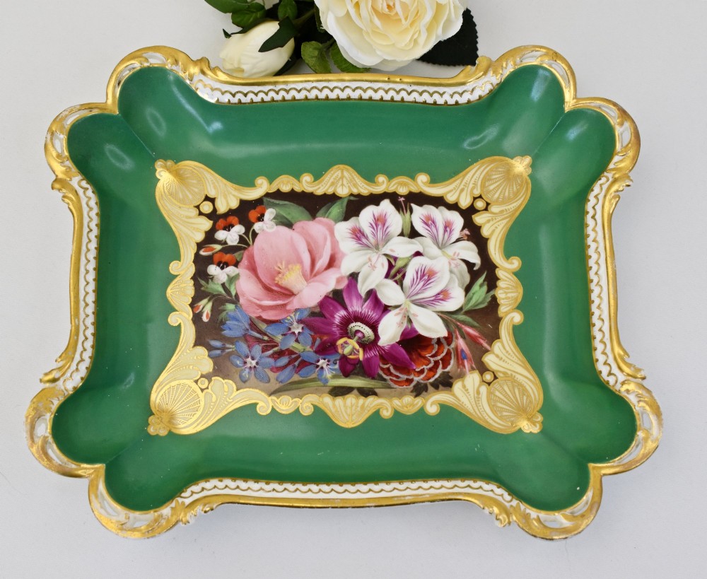A rectangular green porcelain tray with elaborate gold scrollwork framing a hand-painted botanical bouquet in the centre.