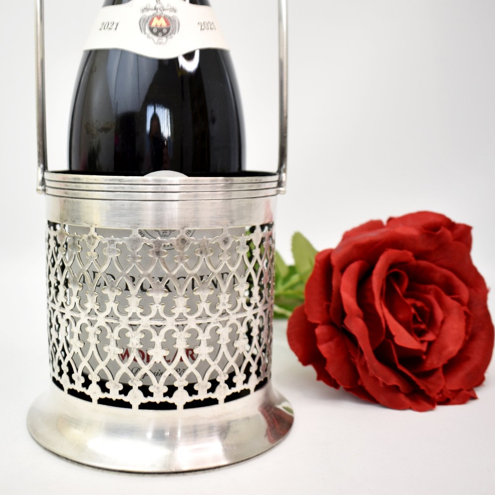 An early 20th-century silver-plated bottle holder featuring pierced geometric lattice fretwork, a flared base, and an upright twin handle. View III