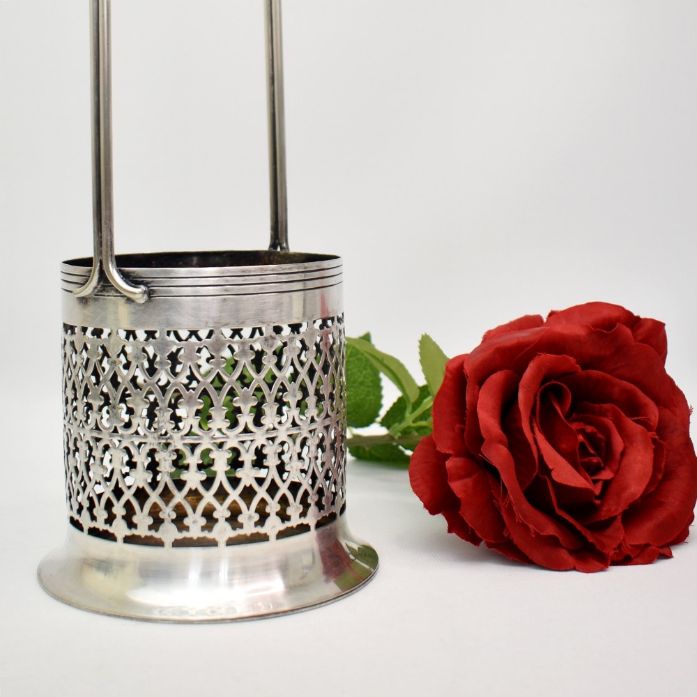 An early 20th-century silver-plated bottle holder featuring pierced geometric lattice fretwork, a flared base, and an upright twin handle.
