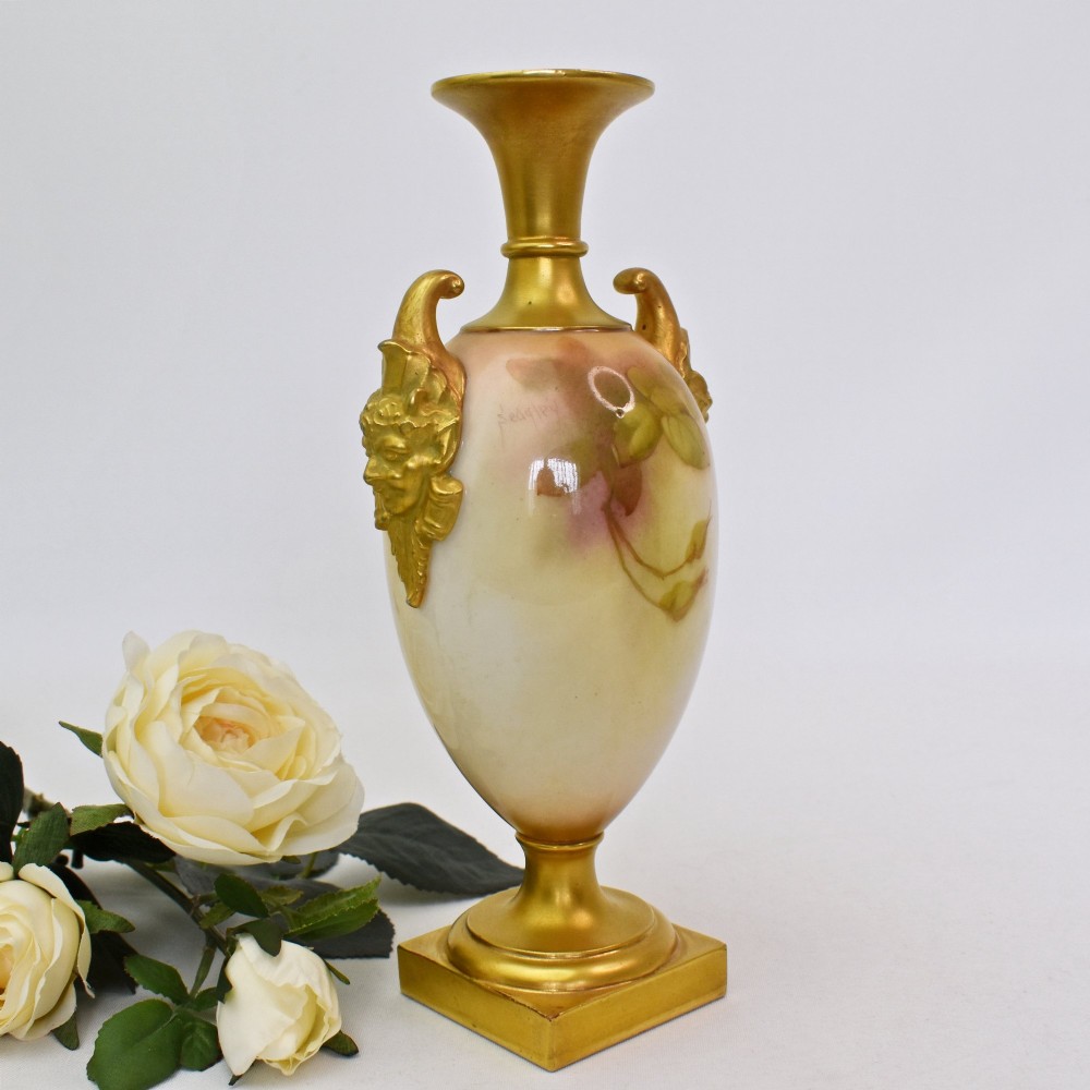 A hand-painted Royal Worcester porcelain vase decorated with pink and red roses, featuring gilded jester mask handles and a square base. View III
