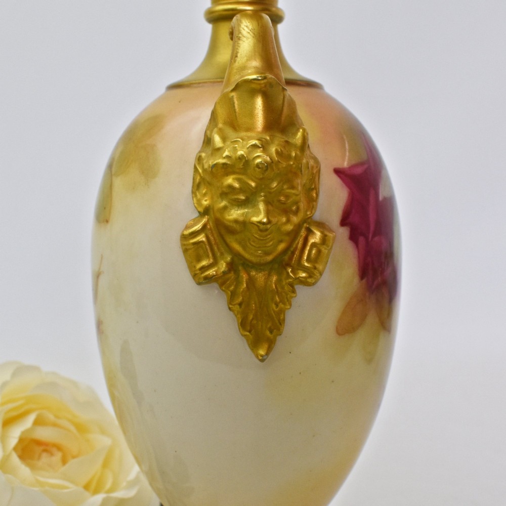 A hand-painted Royal Worcester porcelain vase decorated with pink and red roses, featuring gilded jester mask handles and a square base. View VIII