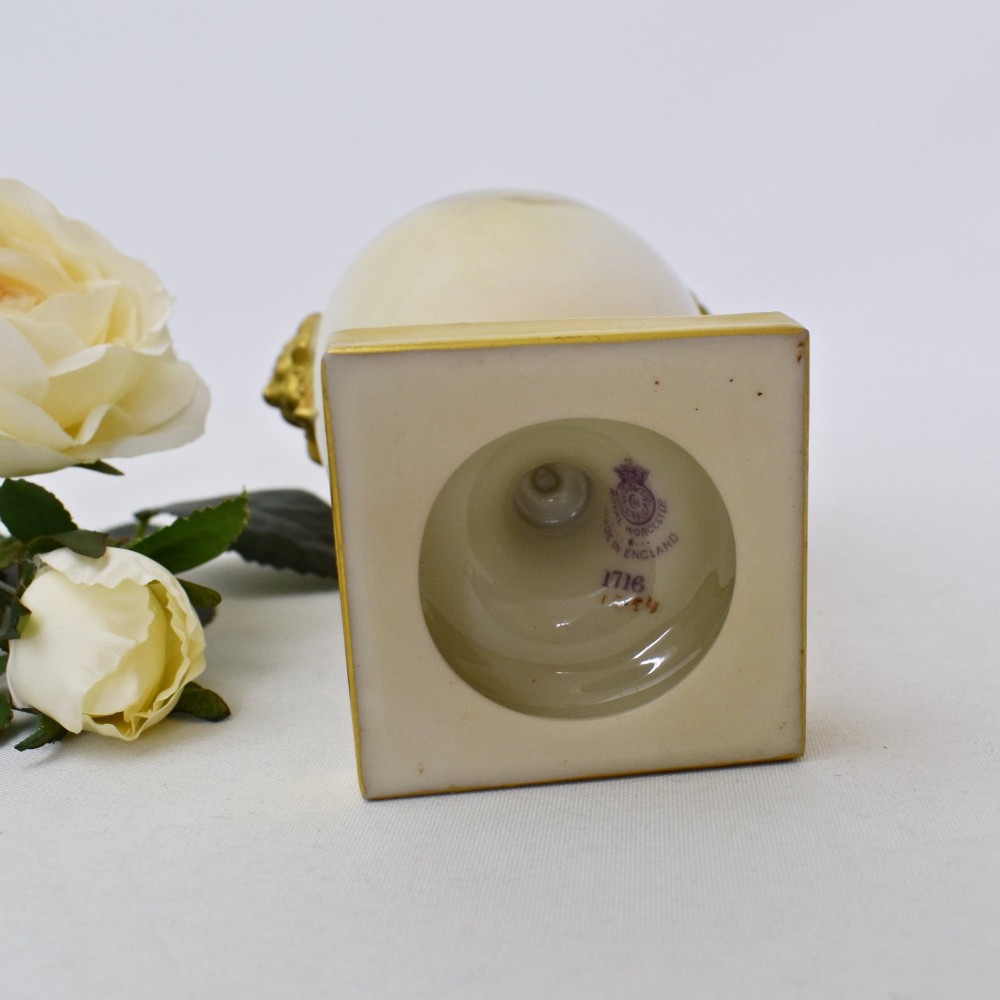 A hand-painted Royal Worcester porcelain vase decorated with pink and red roses, featuring gilded jester mask handles and a square base. View XII