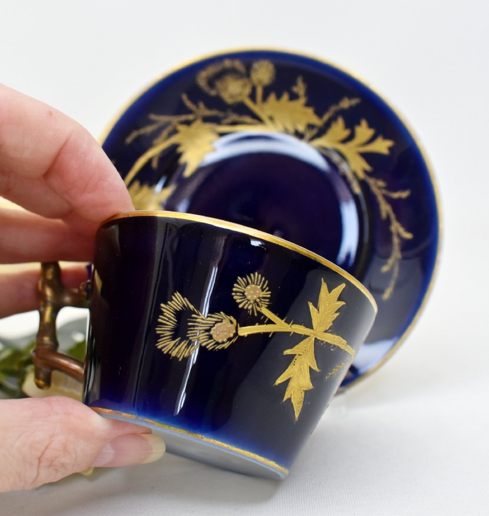 A French porcelain coffee cup and saucer in deep cobalt blue with raised gold gilded thistle motifs and a branch-formed gilt handle. View III