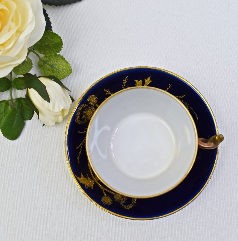 A French porcelain coffee cup and saucer in deep cobalt blue with raised gold gilded thistle motifs and a branch-formed gilt handle. View V