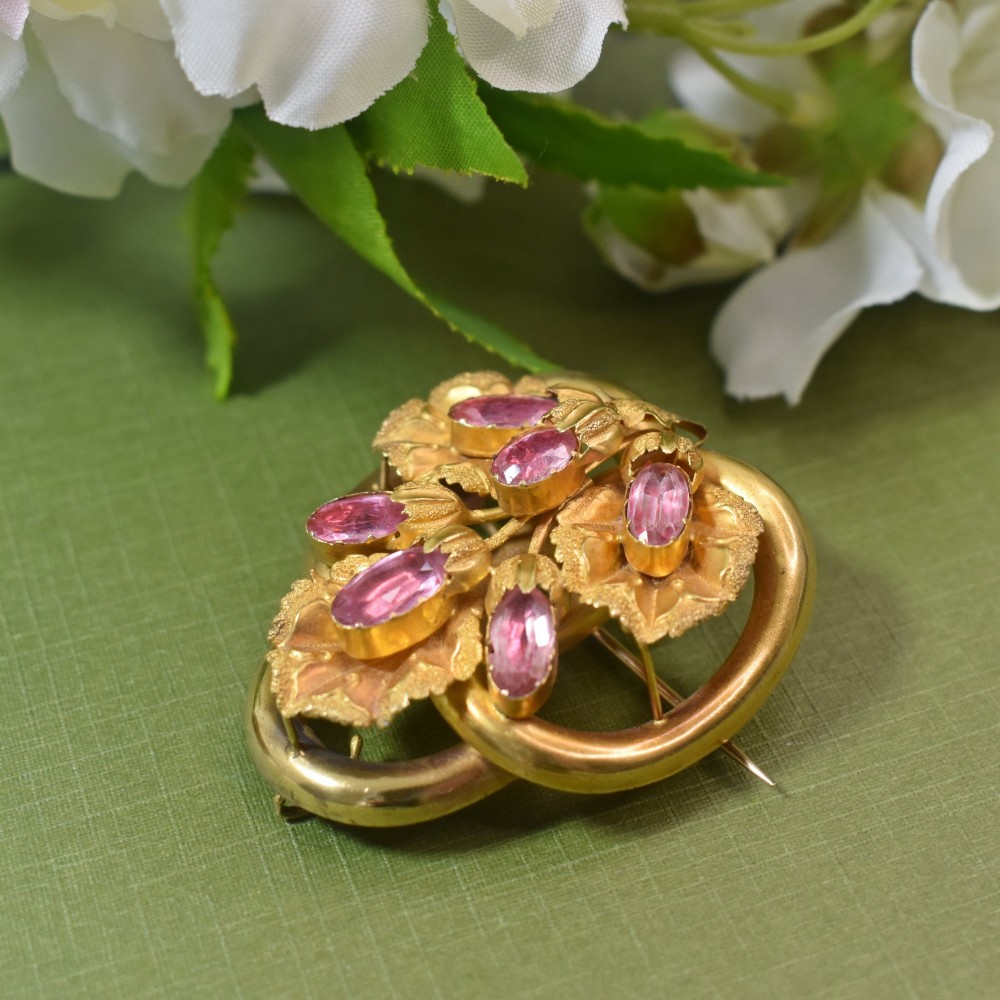 An early Victorian 15ct gold floral brooch featuring oval foil-backed pink topaz gemstones set amongst chased gold leaf and scroll motifs. View III