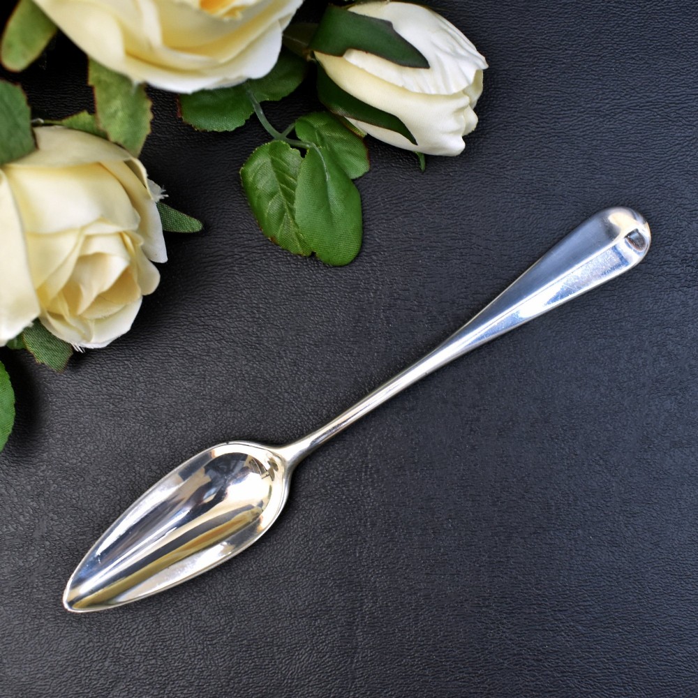A set of six sterling silver grapefruit spoons with pointed bowls and tapered handles on a dark background. View II