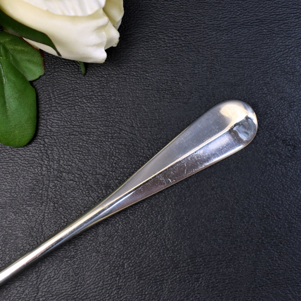 A set of six sterling silver grapefruit spoons with pointed bowls and tapered handles on a dark background. View III