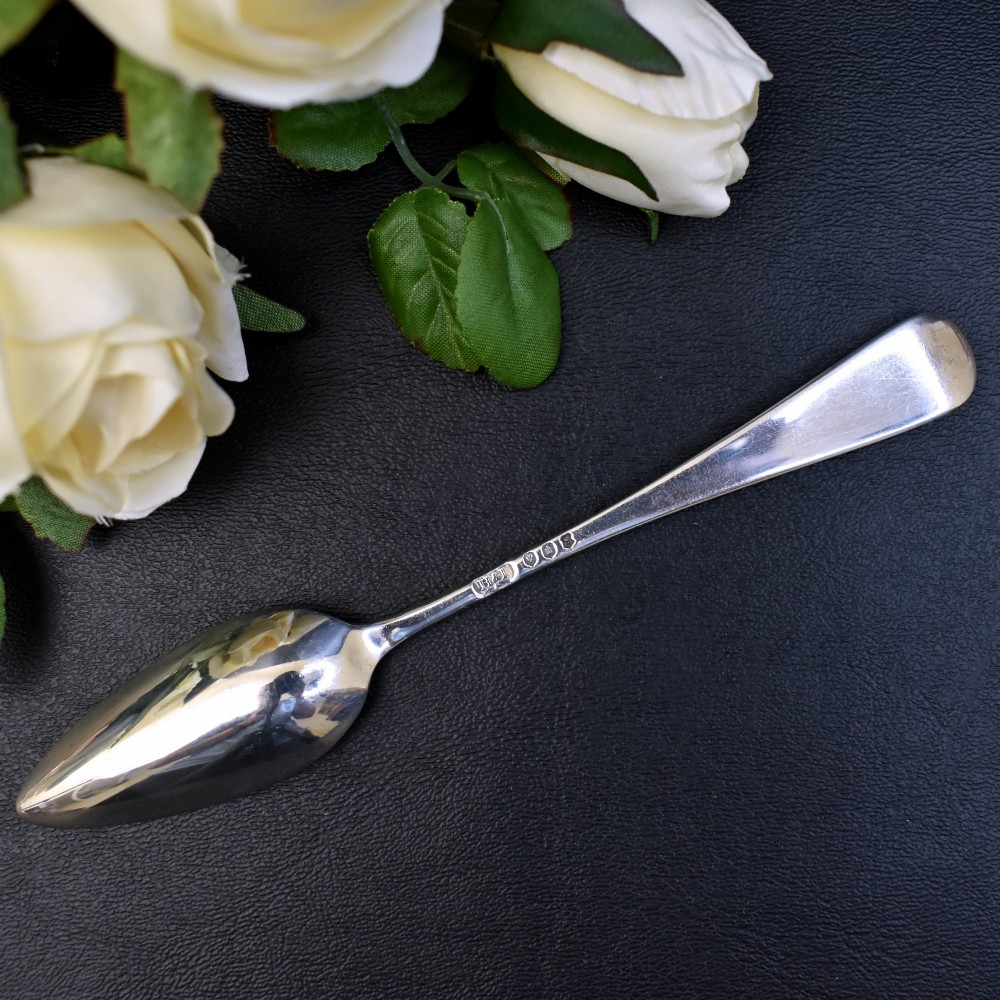 A set of six sterling silver grapefruit spoons with pointed bowls and tapered handles on a dark background. View V