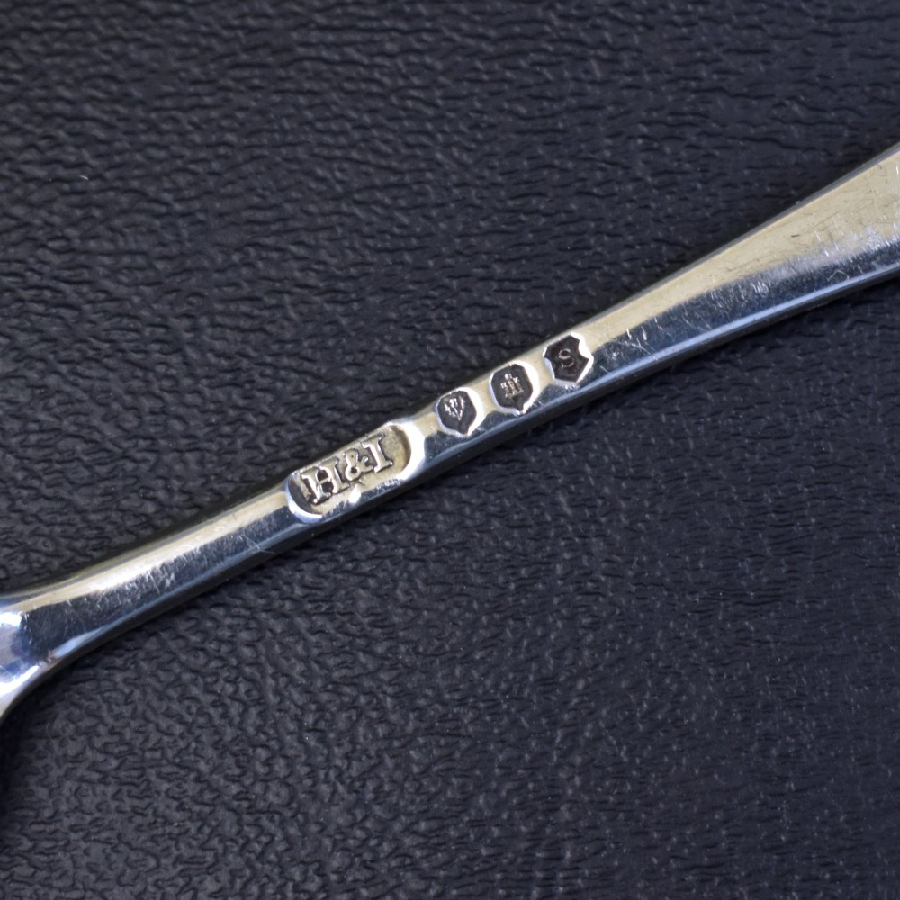 A set of six sterling silver grapefruit spoons with pointed bowls and tapered handles on a dark background. View VI