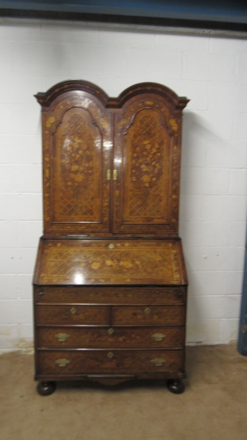 An 18th-century walnut bureau bookcase featuring intricate floral marquetry, a double-domed upper cabinet, a slant-front writing slope, and drawers raised on bun feet. View II