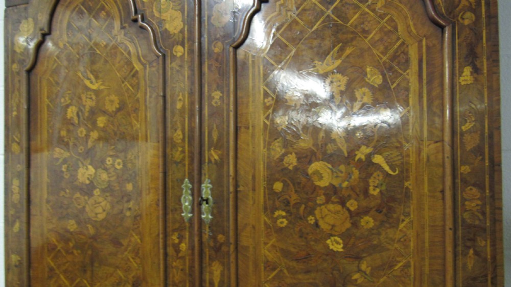 An 18th-century walnut bureau bookcase featuring intricate floral marquetry, a double-domed upper cabinet, a slant-front writing slope, and drawers raised on bun feet. View VII