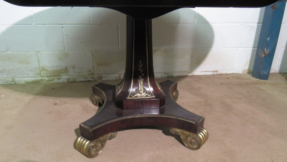 A circular Regency rosewood tilt-top loo table featuring brass marquetry inlay along the perimeter and a pedestal base. View V