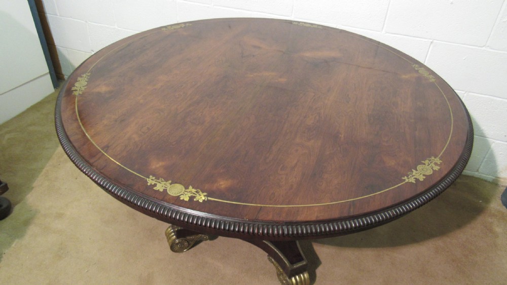 A circular Regency rosewood tilt-top loo table featuring brass marquetry inlay along the perimeter and a pedestal base. View XII