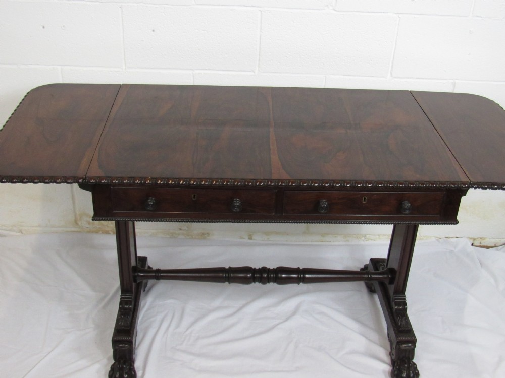 A 19th-century dark rosewood sofa table with two frieze drawers, drop-leaf side flaps, a turned central stretcher, and carved lion paw feet. View X