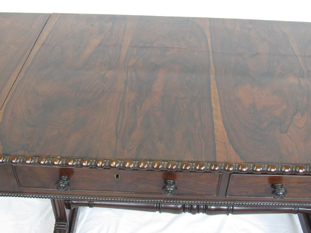 A 19th-century dark rosewood sofa table with two frieze drawers, drop-leaf side flaps, a turned central stretcher, and carved lion paw feet. View XI