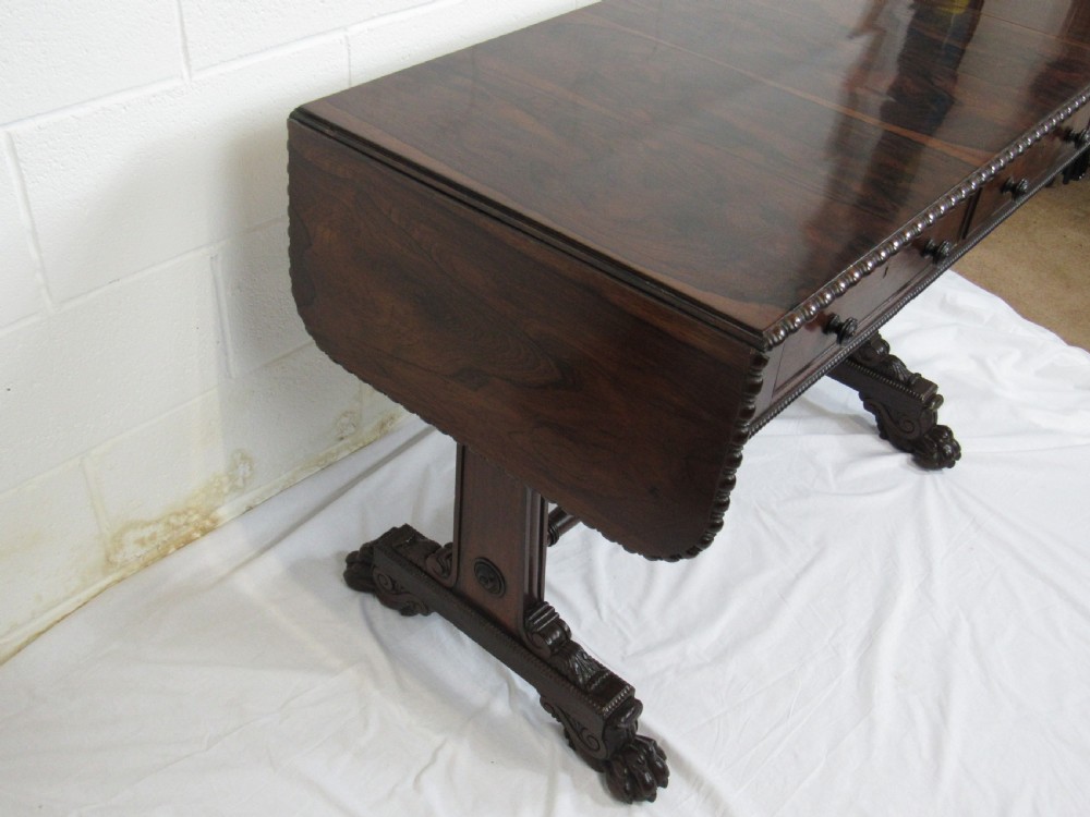 A 19th-century dark rosewood sofa table with two frieze drawers, drop-leaf side flaps, a turned central stretcher, and carved lion paw feet. View XIII