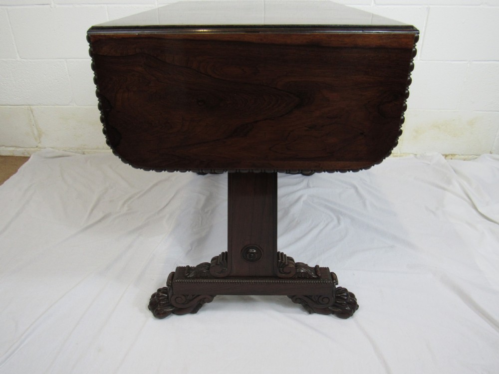 A 19th-century dark rosewood sofa table with two frieze drawers, drop-leaf side flaps, a turned central stretcher, and carved lion paw feet. View XIV