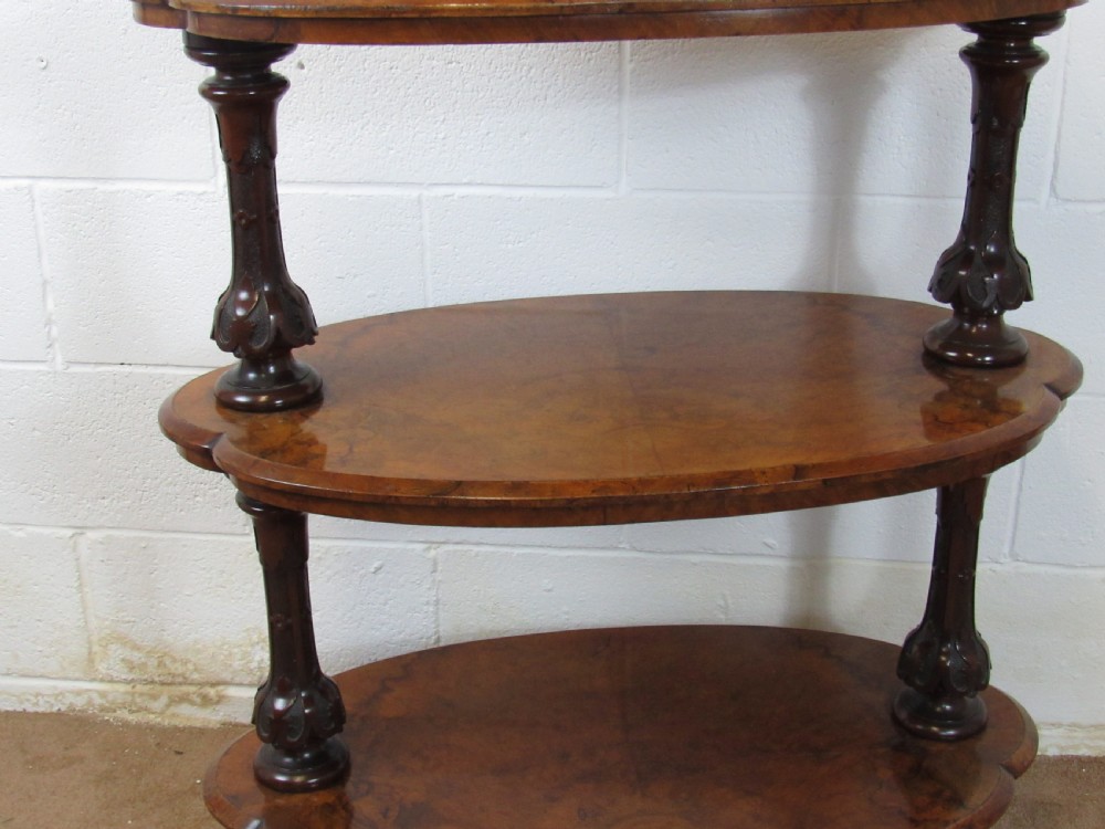 A Victorian burr walnut three-tier oval what-not etagere with turned columns, top finials, and carved feet on castors. View II