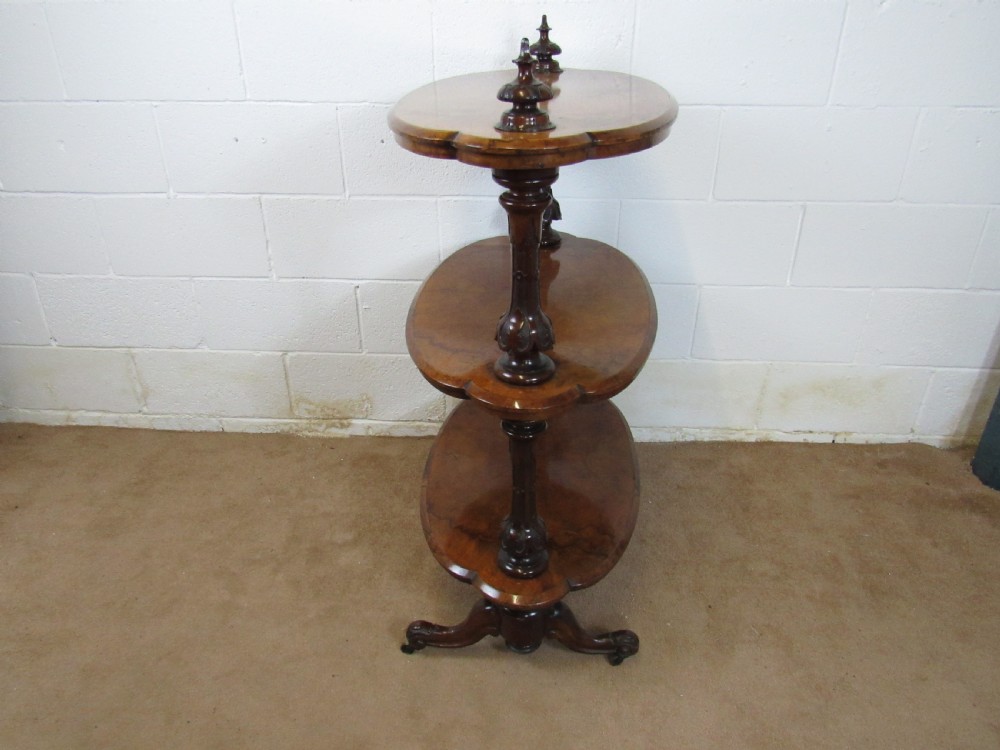 A Victorian burr walnut three-tier oval what-not etagere with turned columns, top finials, and carved feet on castors. View III