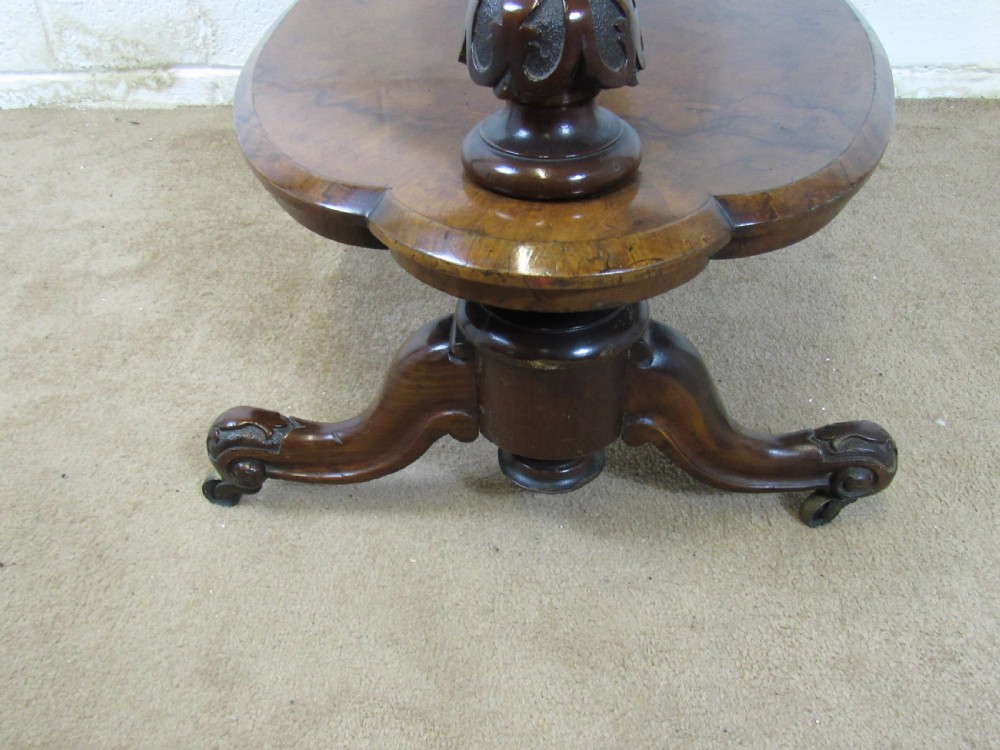 A Victorian burr walnut three-tier oval what-not etagere with turned columns, top finials, and carved feet on castors. View VI