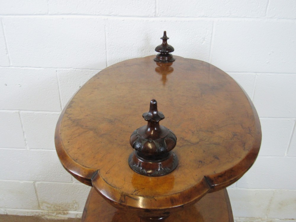A Victorian burr walnut three-tier oval what-not etagere with turned columns, top finials, and carved feet on castors. View IX