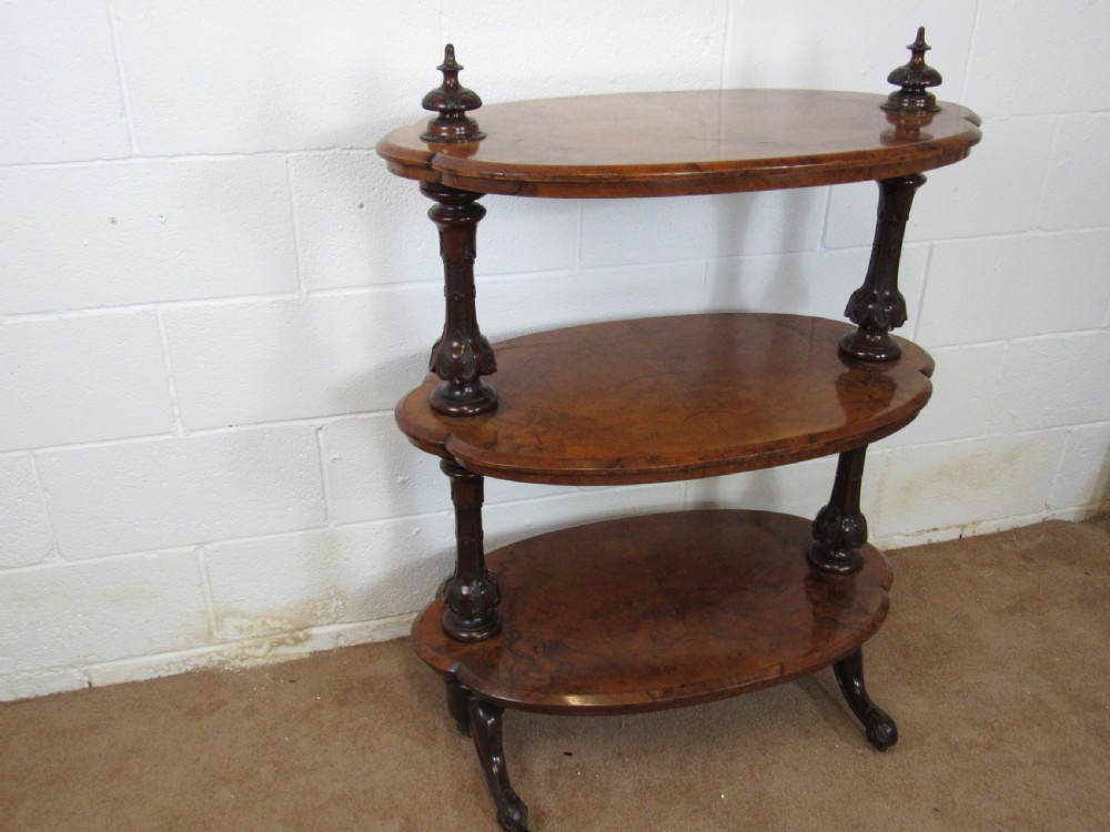 A Victorian burr walnut three-tier oval what-not etagere with turned columns, top finials, and carved feet on castors. View XV