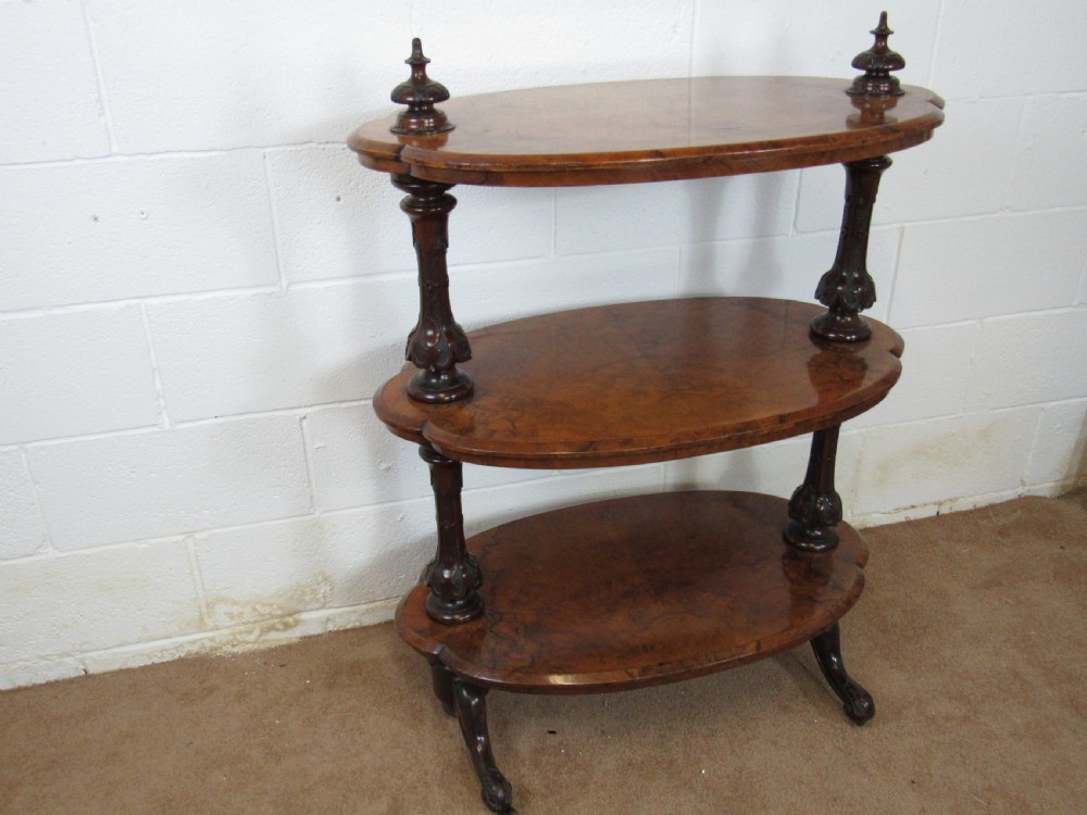 A Victorian burr walnut three-tier oval what-not etagere with turned columns, top finials, and carved feet on castors. View XVI