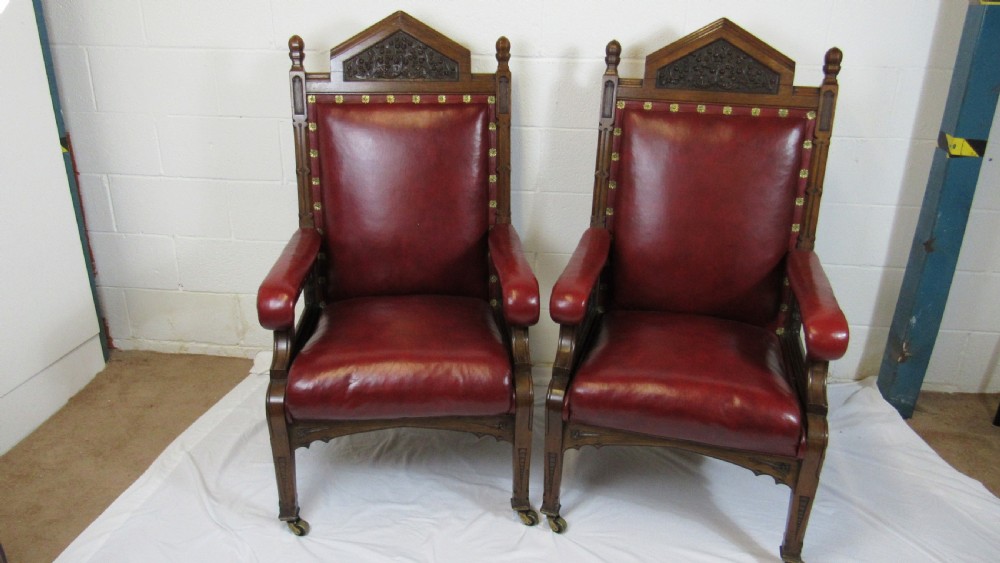A pair of high-backed Gothic Revival armchairs crafted from carved dark wood and upholstered in deep red leather with brass stud detail. View II