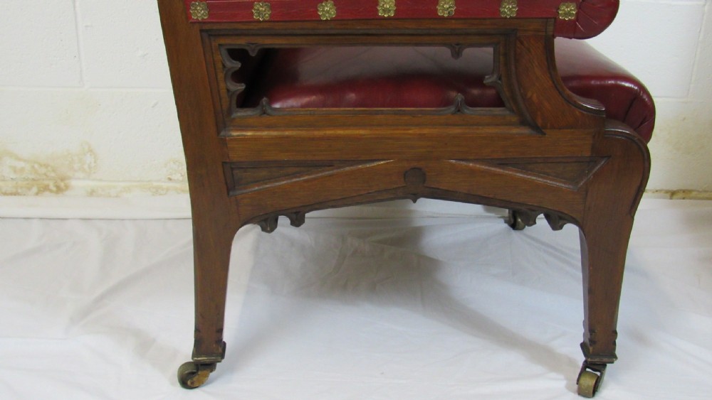 A pair of high-backed Gothic Revival armchairs crafted from carved dark wood and upholstered in deep red leather with brass stud detail. View XI