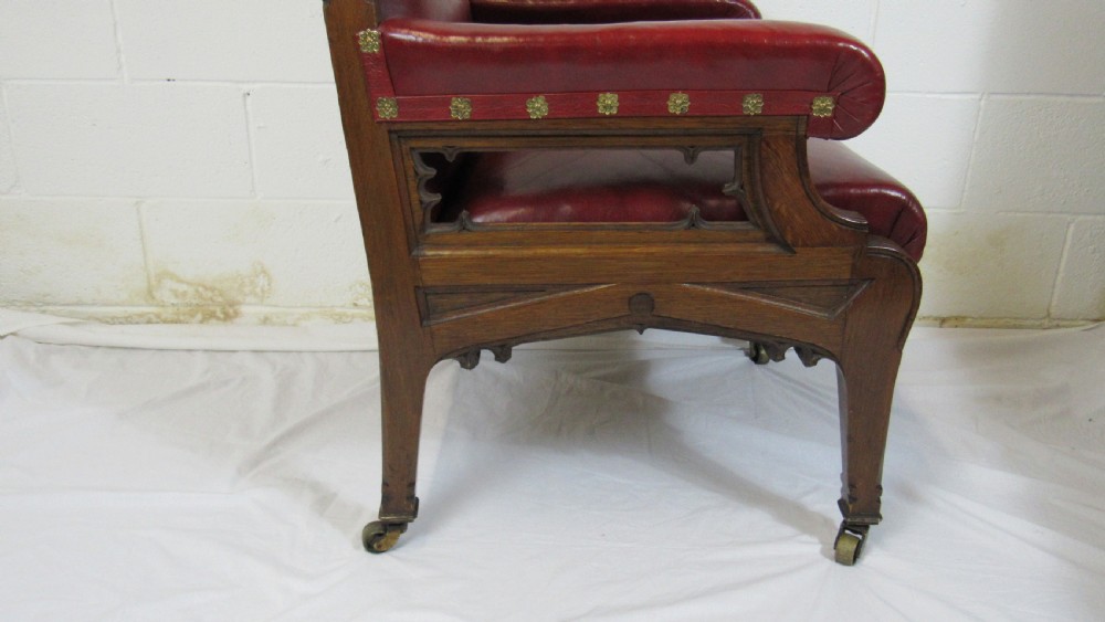 A pair of high-backed Gothic Revival armchairs crafted from carved dark wood and upholstered in deep red leather with brass stud detail. View XIII
