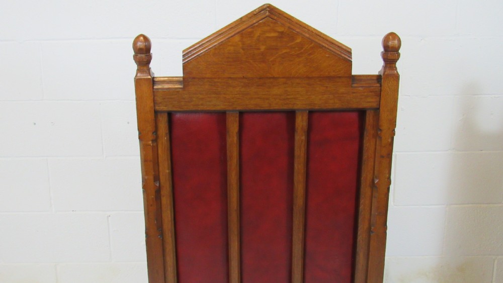 A pair of high-backed Gothic Revival armchairs crafted from carved dark wood and upholstered in deep red leather with brass stud detail. View XVI