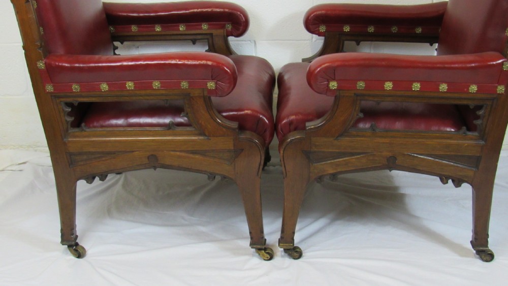 A pair of high-backed Gothic Revival armchairs crafted from carved dark wood and upholstered in deep red leather with brass stud detail. View XVIII