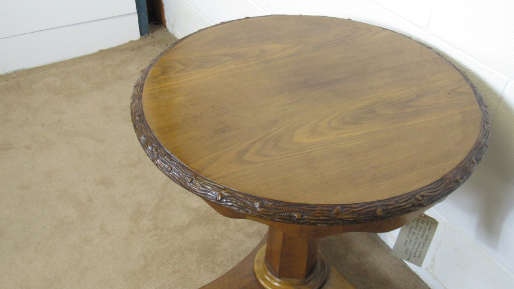 A circular 19th-century mahogany centre table with a carved rim, central pillar, and tri-form base with carved lion paw feet on brass castors. View II