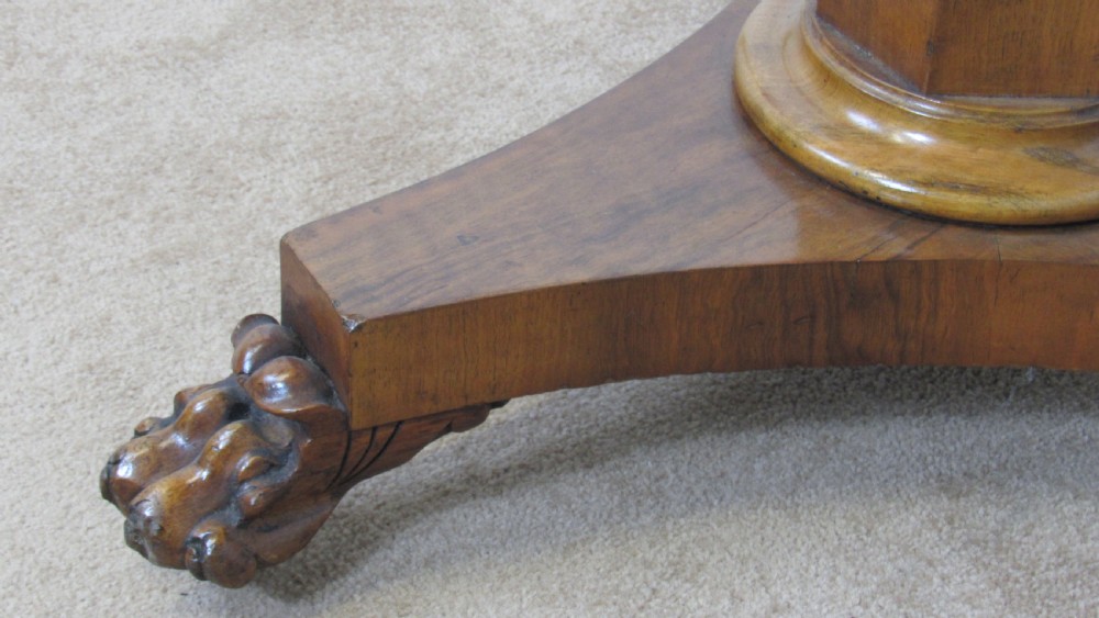 A circular 19th-century mahogany centre table with a carved rim, central pillar, and tri-form base with carved lion paw feet on brass castors. View VII
