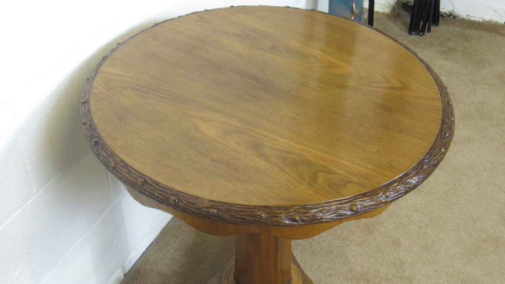 A circular 19th-century mahogany centre table with a carved rim, central pillar, and tri-form base with carved lion paw feet on brass castors. View XI