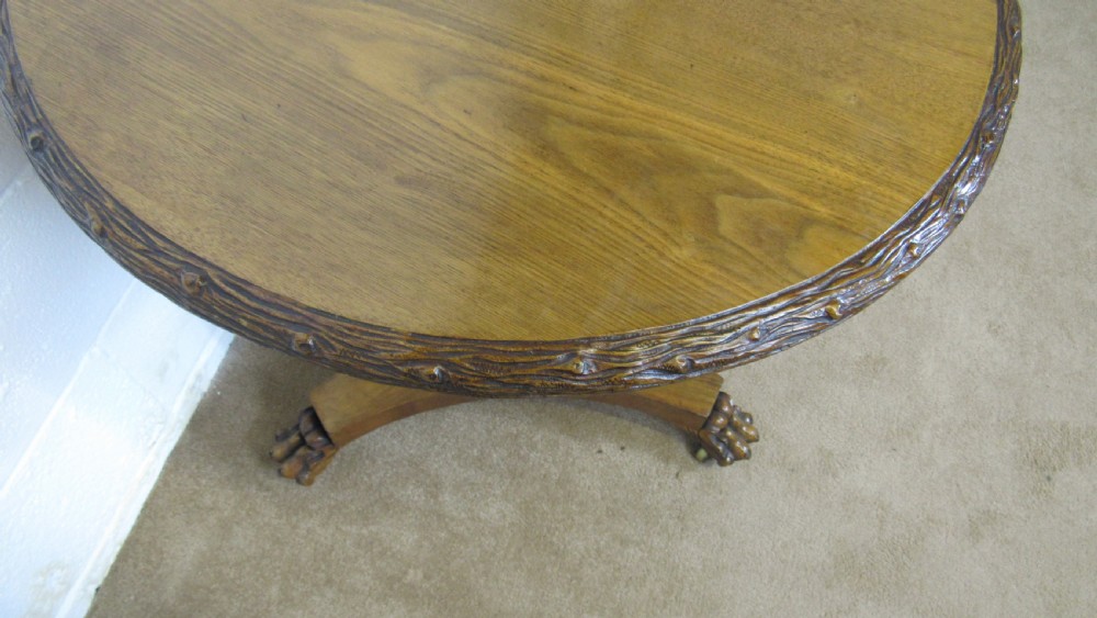 A circular 19th-century mahogany centre table with a carved rim, central pillar, and tri-form base with carved lion paw feet on brass castors. View XII