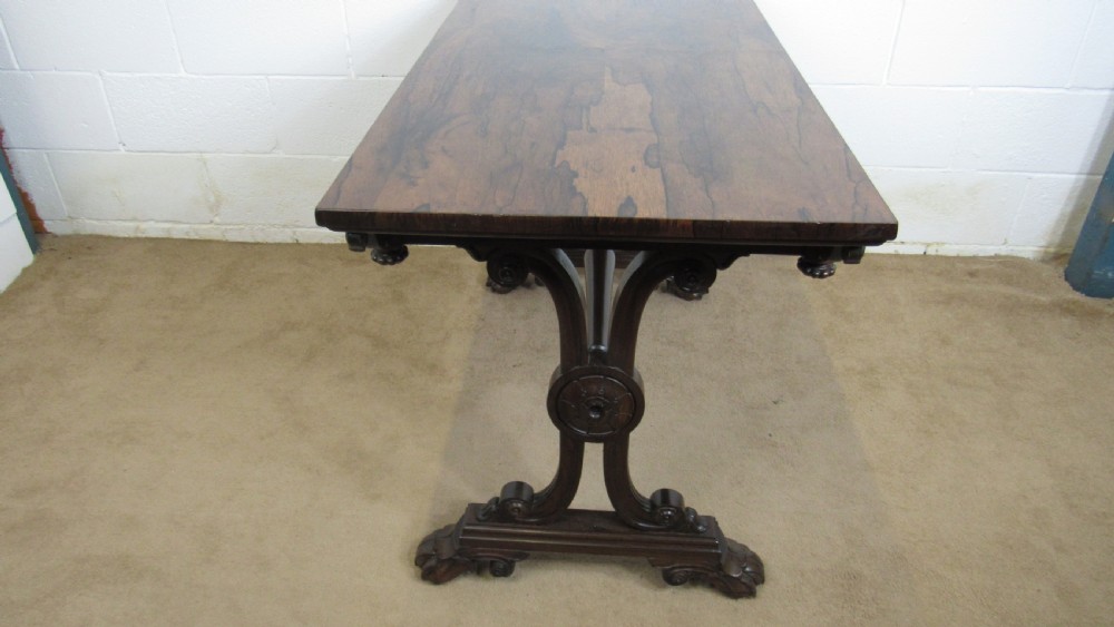 A dark rosewood library table featuring a polished rectangular top, frieze drawer, carved scroll trestle ends, a turned stretcher, and carved feet. View II