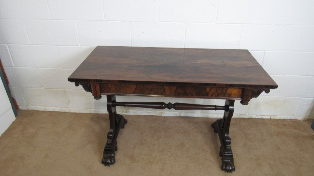 A dark rosewood library table featuring a polished rectangular top, frieze drawer, carved scroll trestle ends, a turned stretcher, and carved feet. View III