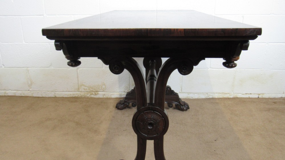 A dark rosewood library table featuring a polished rectangular top, frieze drawer, carved scroll trestle ends, a turned stretcher, and carved feet. View VII