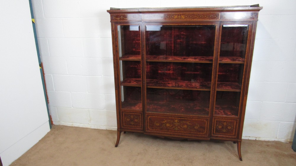 An Edwardian fiddleback mahogany display cabinet featuring glazed doors, detailed floral marquetry inlay on the lower panels, and square tapered legs.