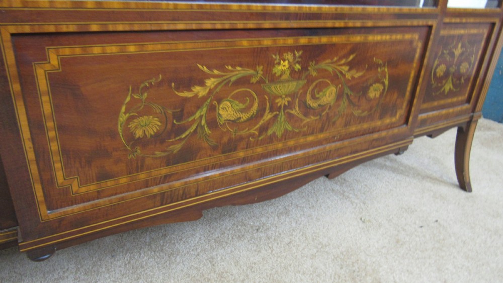 An Edwardian fiddleback mahogany display cabinet featuring glazed doors, detailed floral marquetry inlay on the lower panels, and square tapered legs. View X