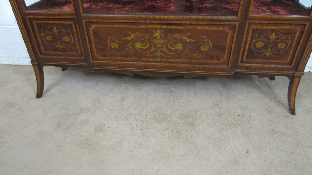An Edwardian fiddleback mahogany display cabinet featuring glazed doors, detailed floral marquetry inlay on the lower panels, and square tapered legs. View XI